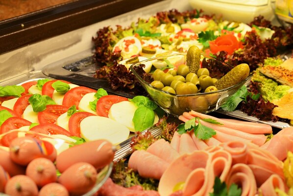 A buffet with various cold cuts, cheeses, and salads.