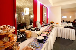 Mesa de buffet con diversas opciones de comida y un espejo grande.