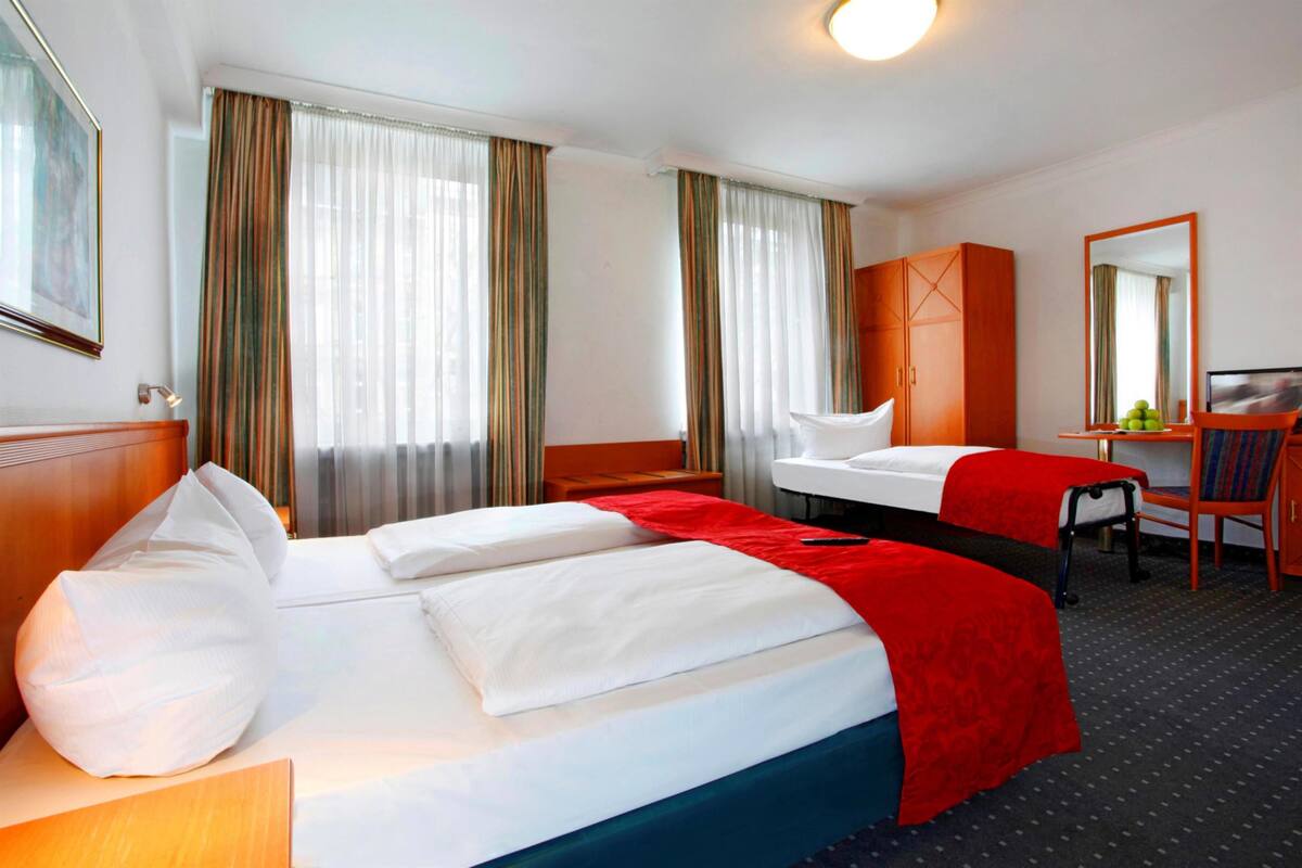 Una habitación de hotel con una cama grande, un escritorio, una silla y un armario.