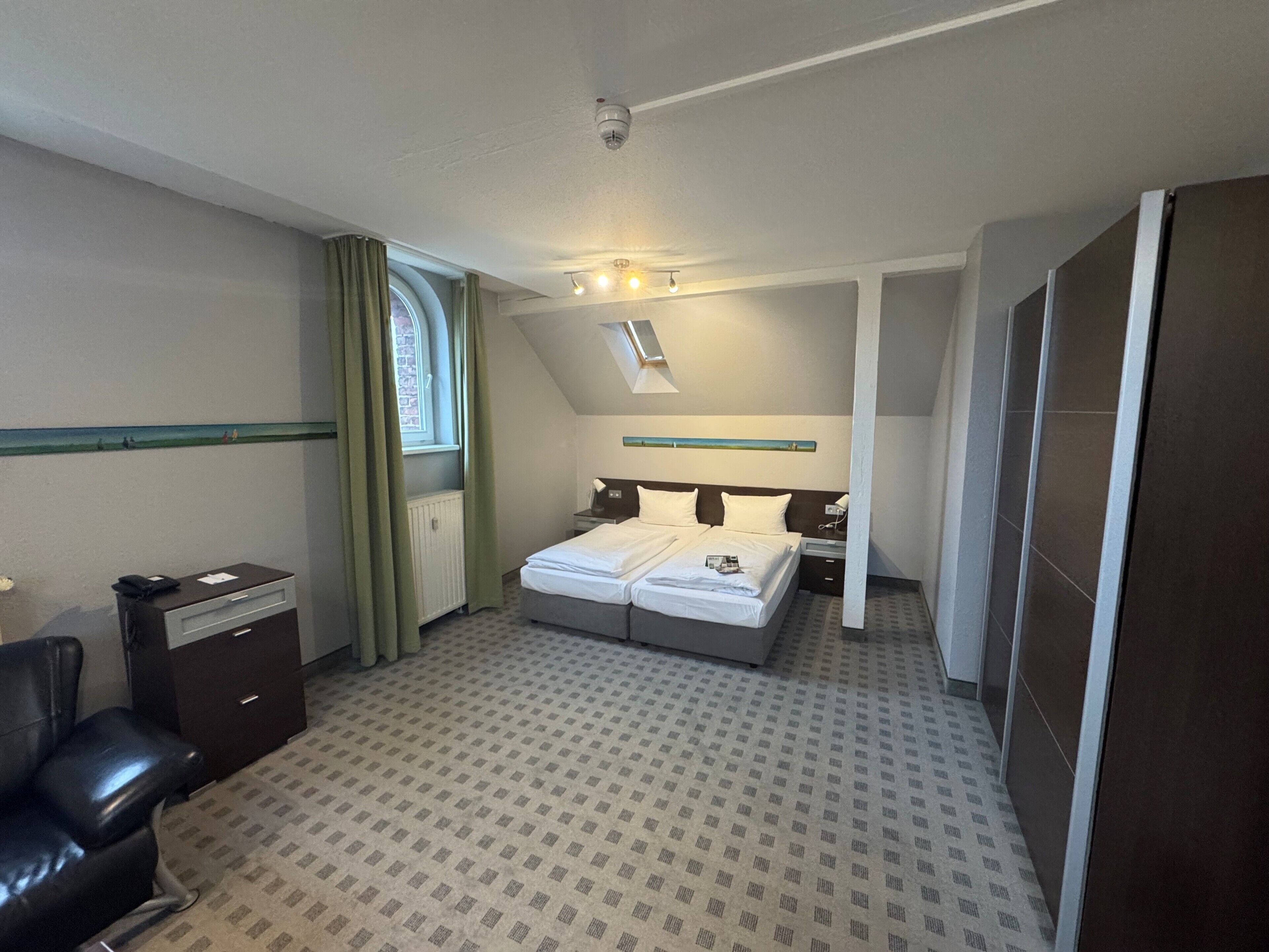 Habitación de hotel con cama, escritorio, silla, ventana y puerta.