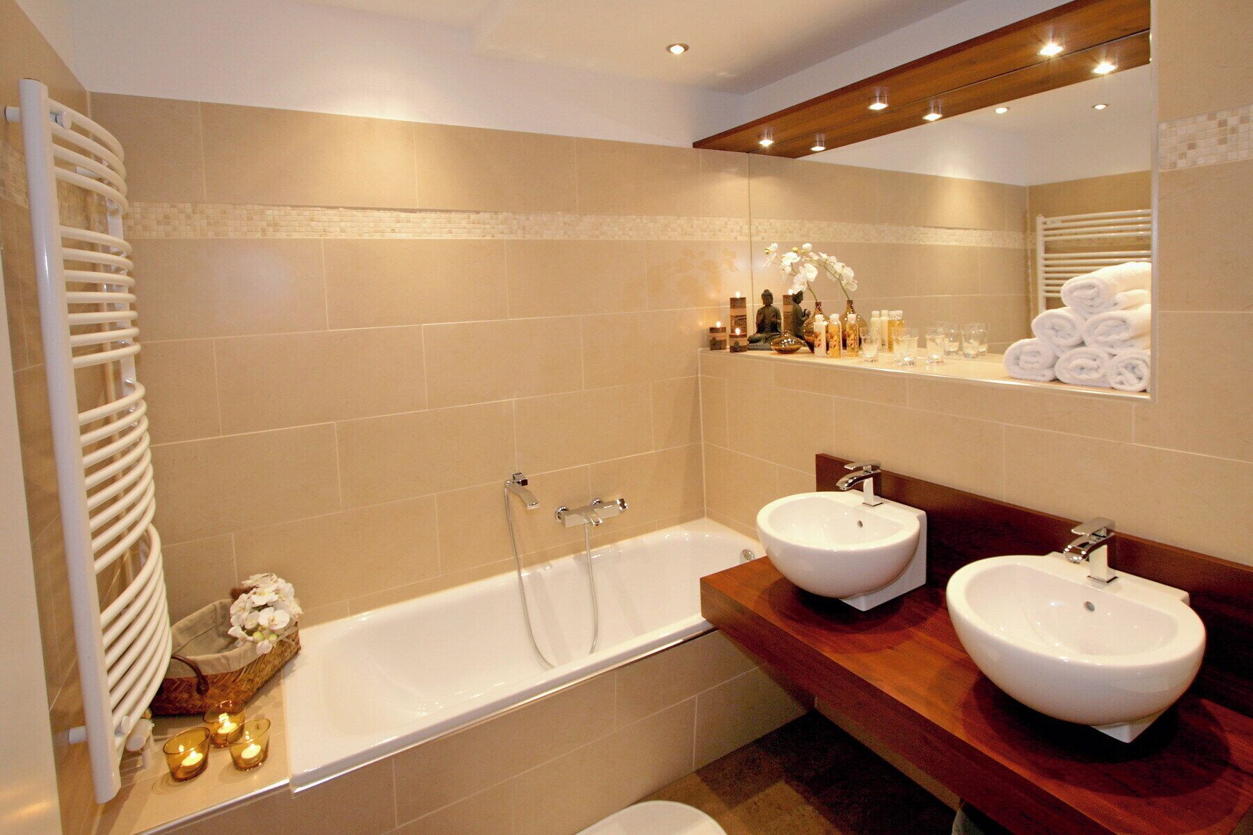 A bathroom with a bathtub, two sinks, a towel rack, and a shelf with toiletries.