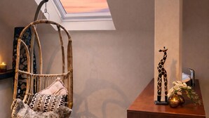 A room with a skylight, a woven chair, a giraffe figurine, and a wooden desk. - Hotel Dampfmühle (Neukirchen-Vluyn)