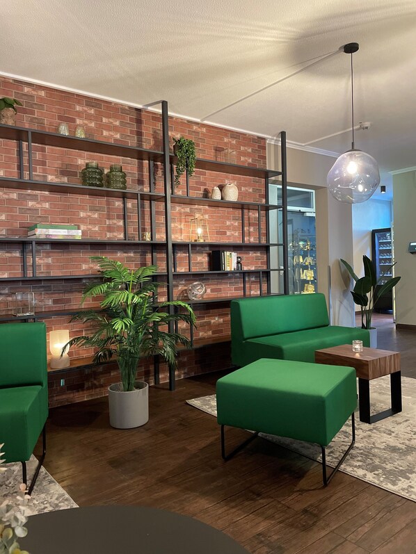 Relax in this stylish living room with a brick accent wall, green seating, and a glass shelving unit.