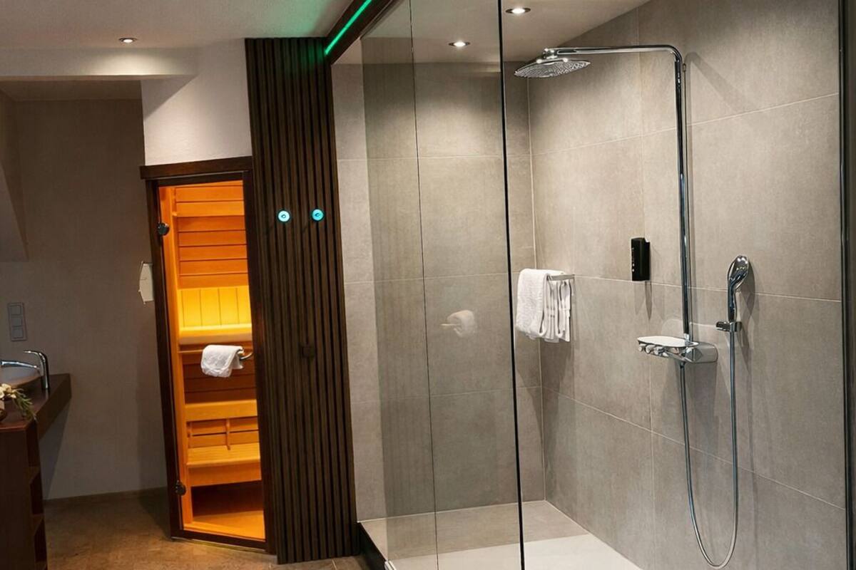A modern bathroom with a glass-enclosed shower, a wooden vanity, and recessed ceiling lighting.