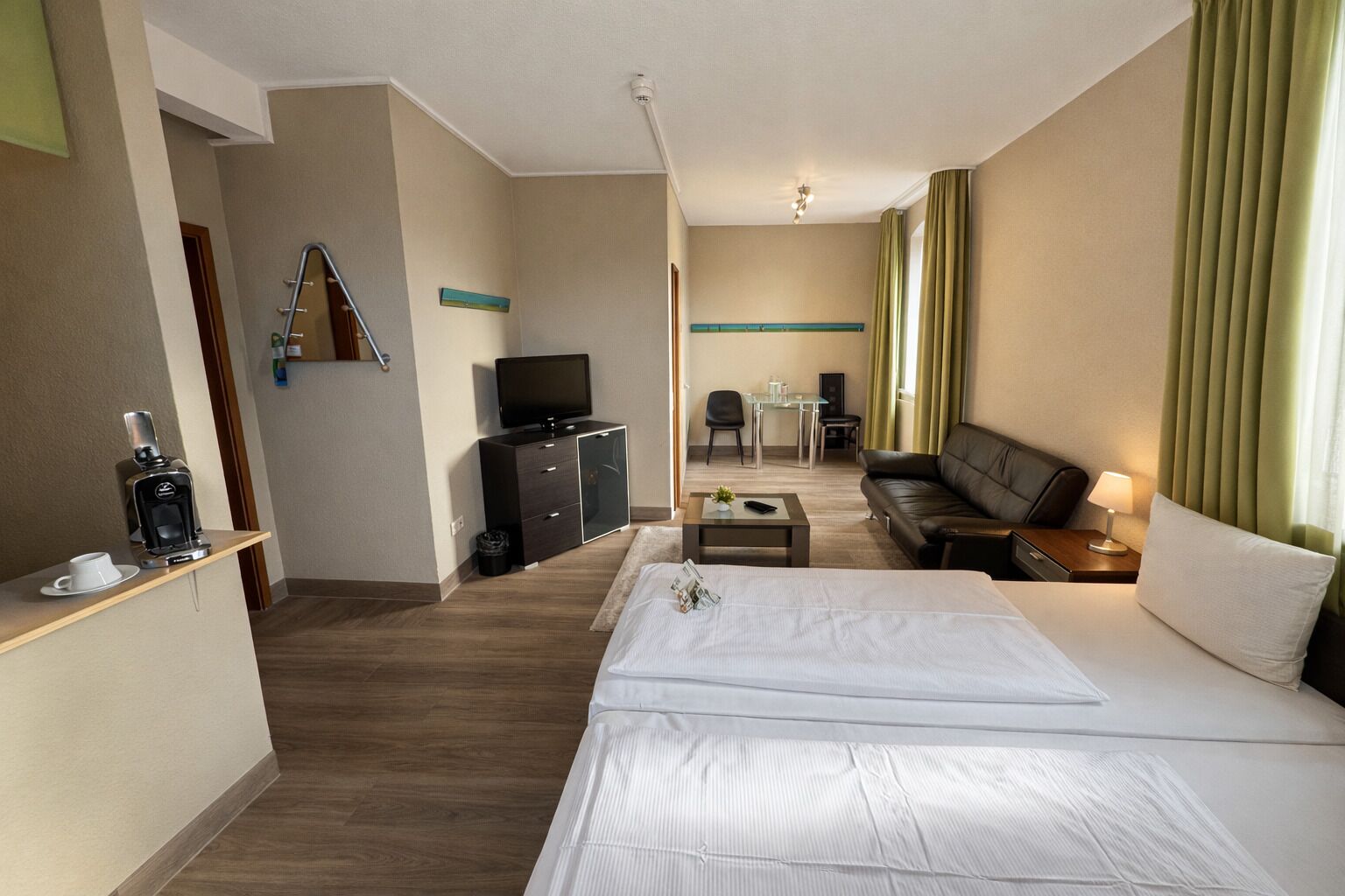 Una habitación de hotel con cama, televisor, escritorio, sofá y cafetera.