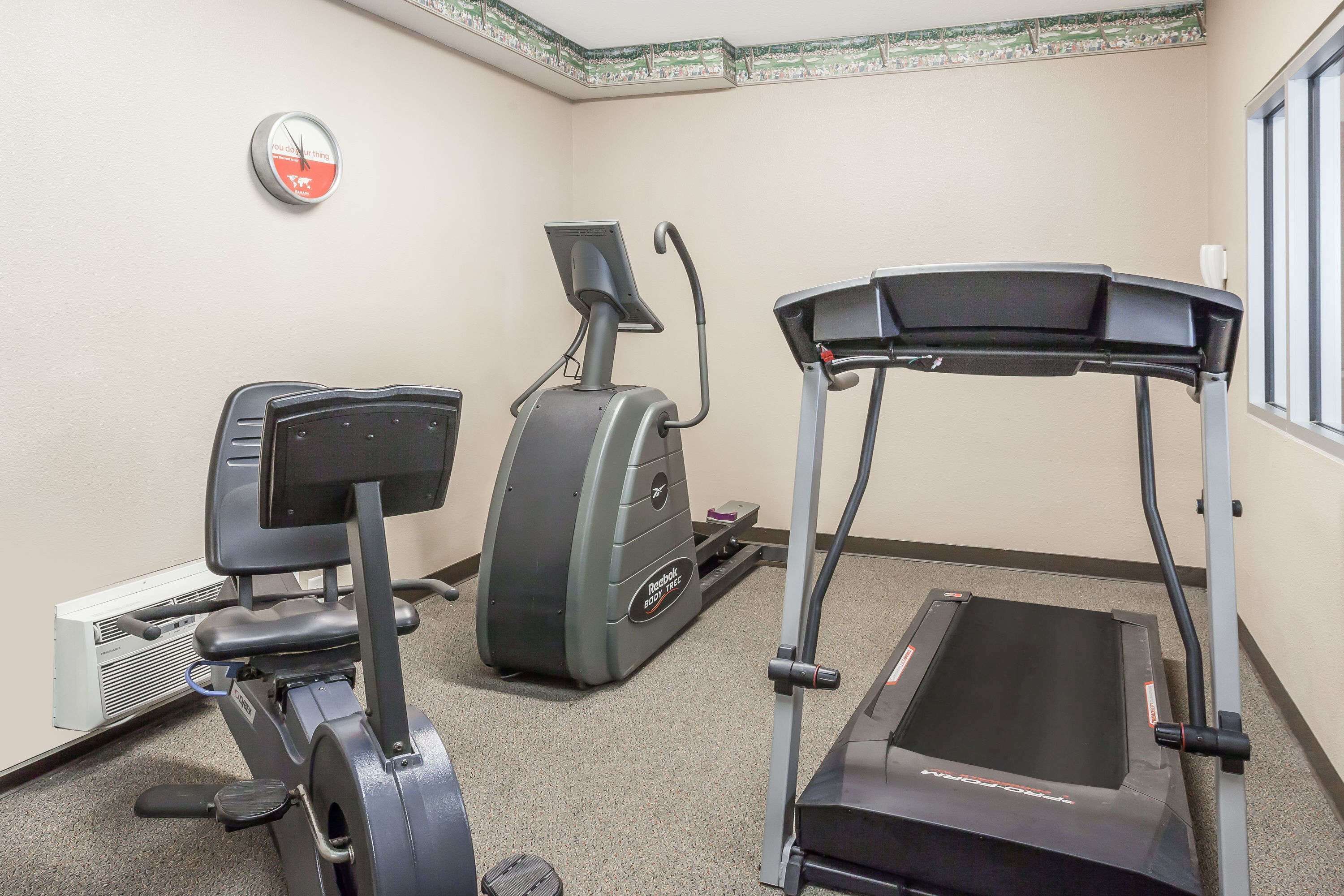 Un gimnasio con cinta de correr, elíptica y bicicleta estática.