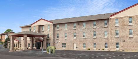 A multi-story hotel with a brick facade, a covered entrance, and a parking lot.