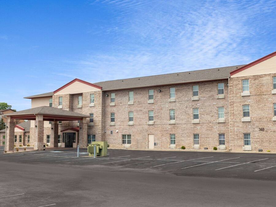 A multi-story hotel with a brick facade, a covered entrance, and a parking lot.