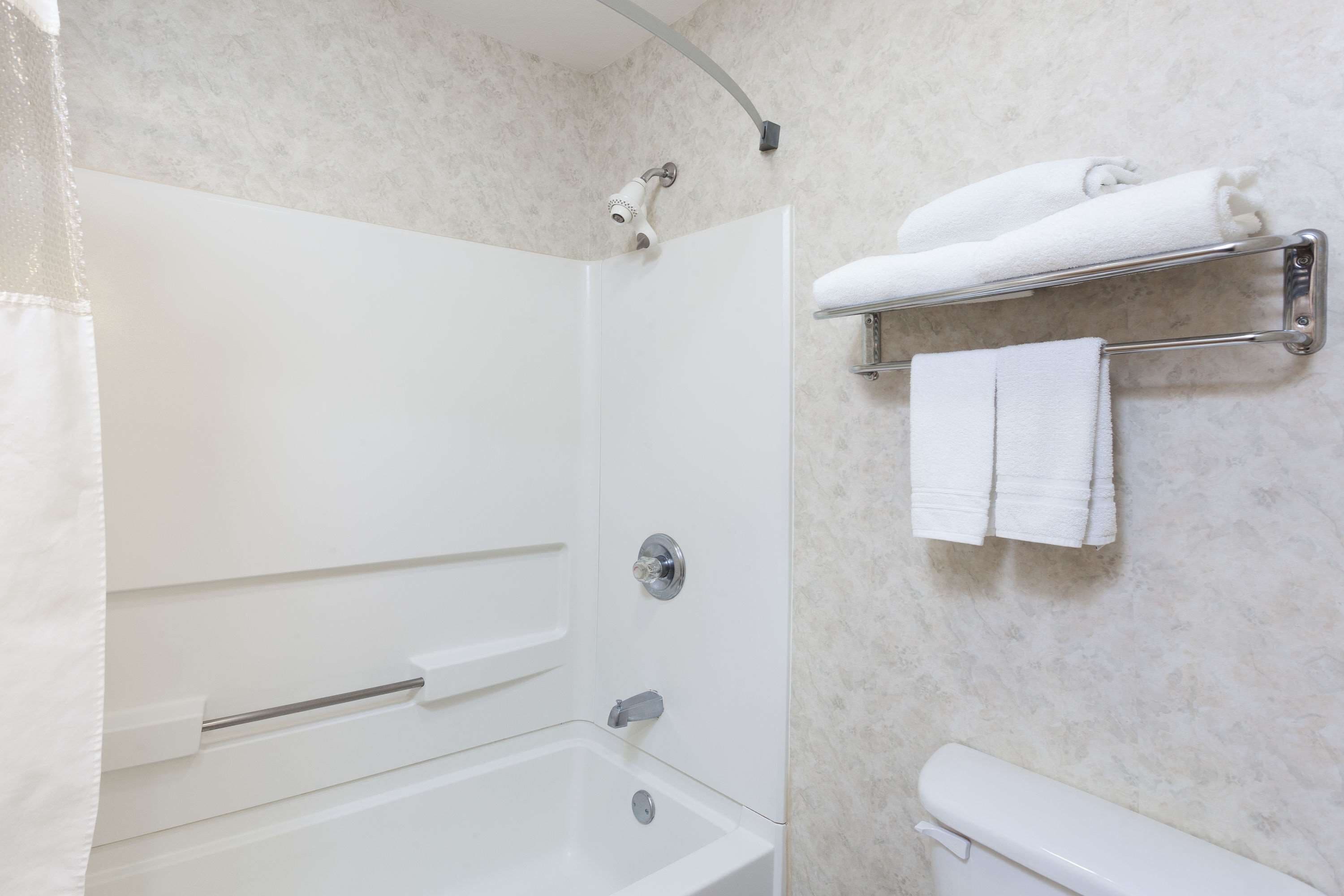 A bathroom with a bathtub, a toilet, and a towel rack.
