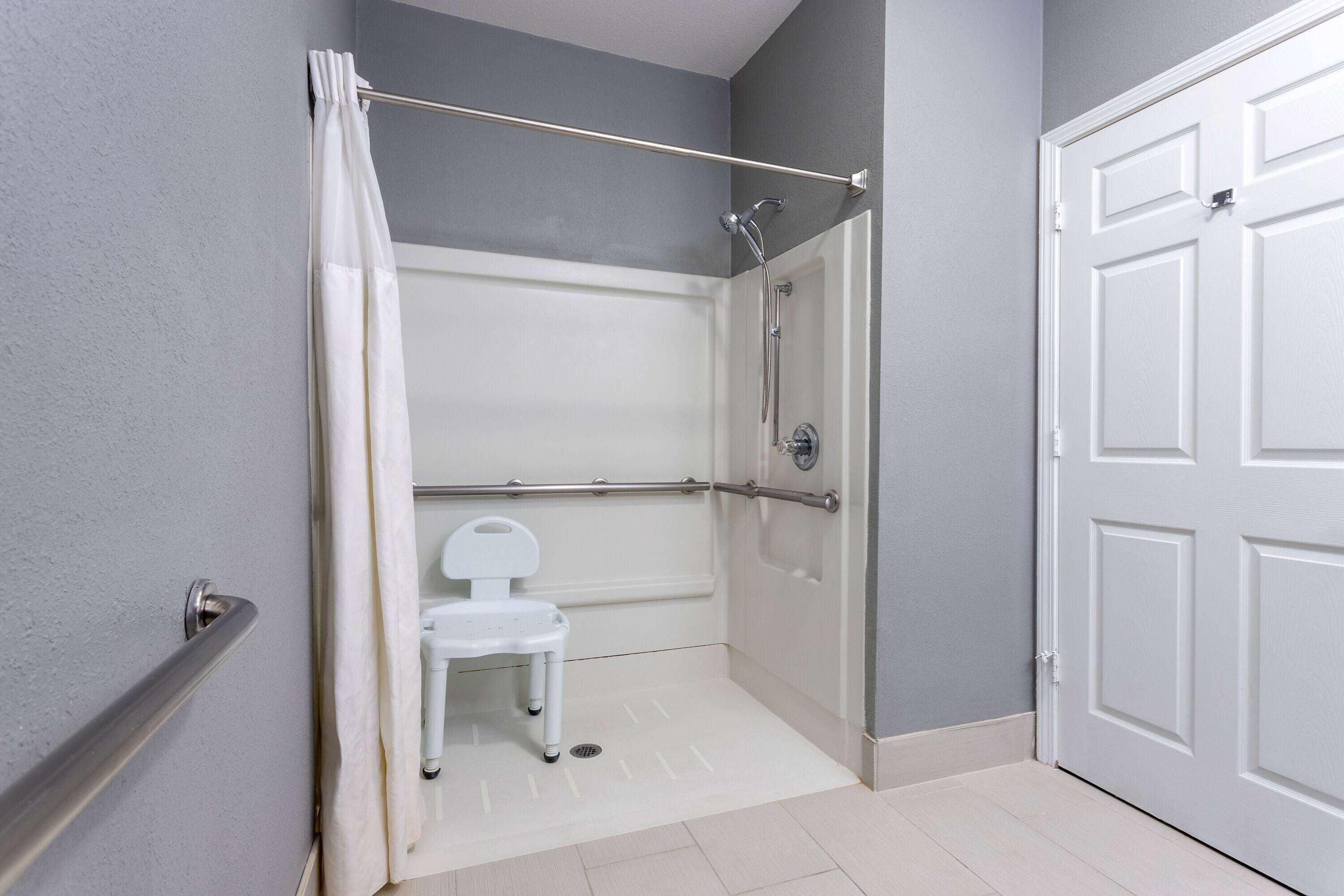 Baño con ducha, inodoro y puerta blancos.