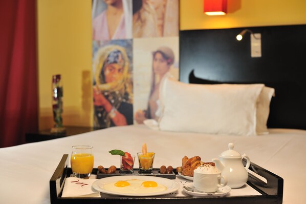 A breakfast tray with eggs, juice, and pastries on a hotel bed. - Mercure Alger Aeroport (Algiers)
