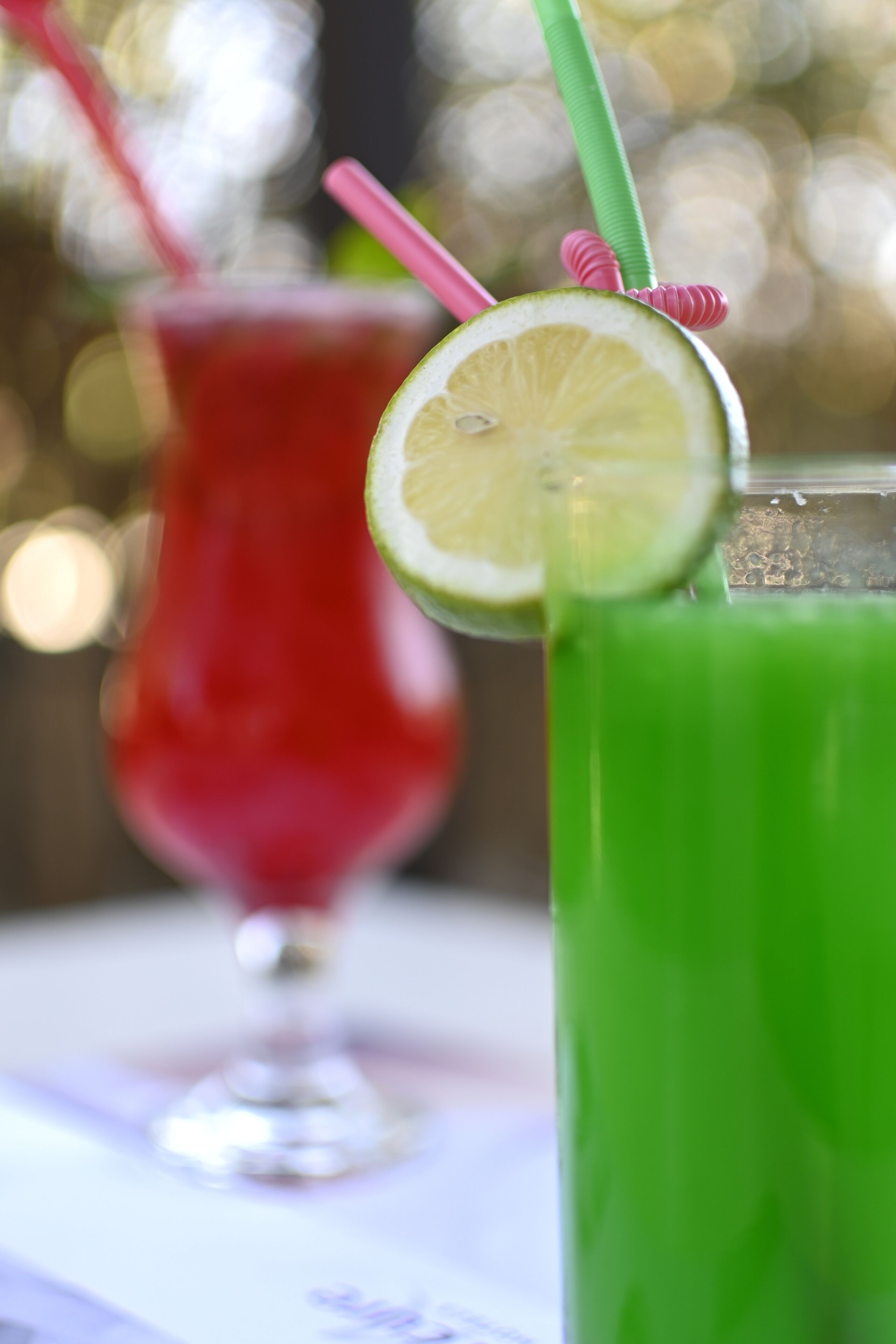 Dos bebidas con pajitas y una rodaja de lima en el borde.
