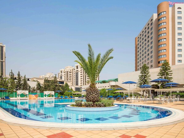 Una piscina al aire libre, sombrillas, sillones reclinables de piscina