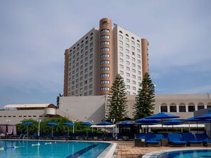 A hotel with a swimming pool, lounge chairs, and umbrellas. - Mercure Alger Aeroport (Algiers)