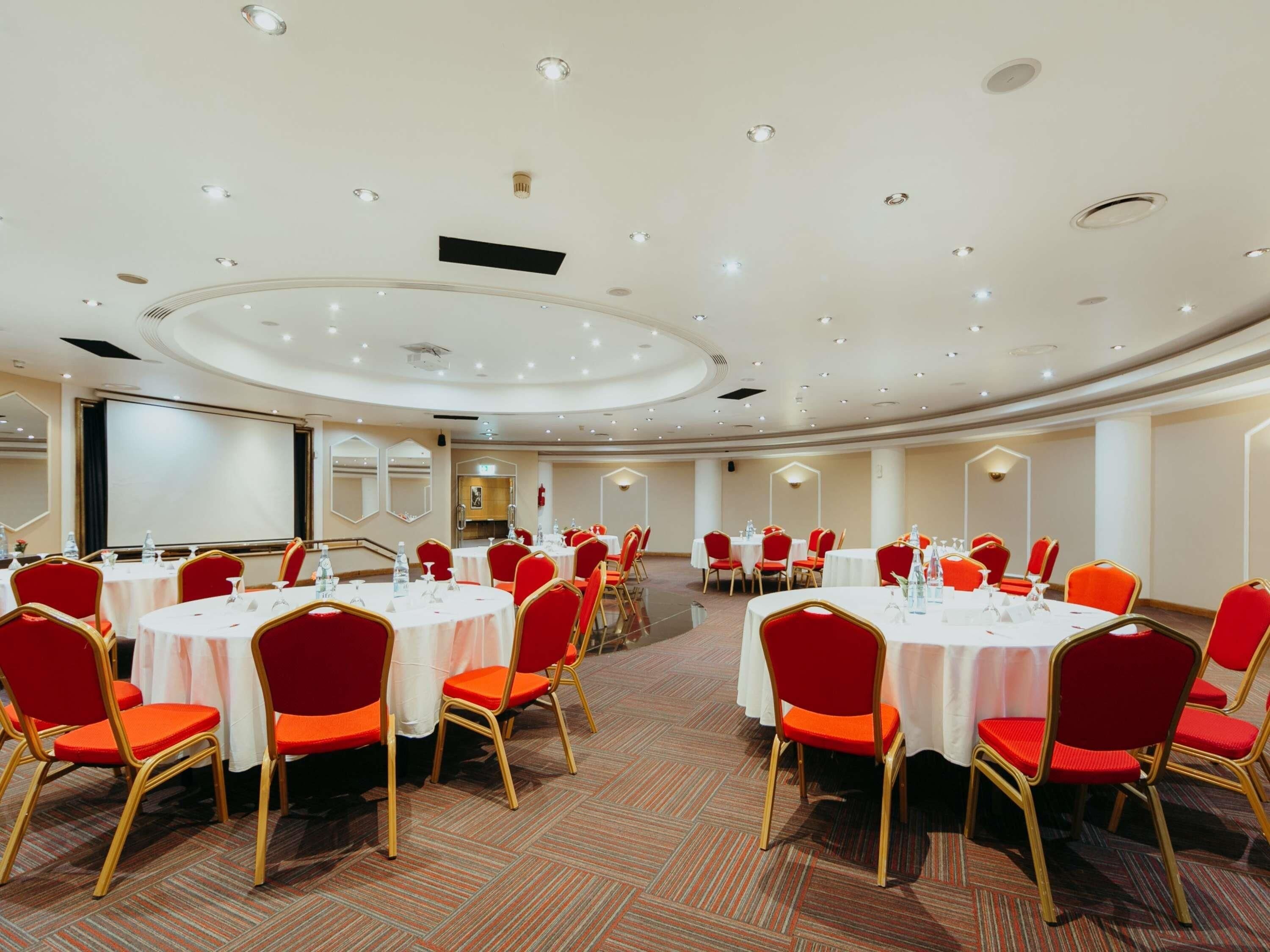 A conference room with multiple tables and chairs, equipped with nameplates and water bottles.
