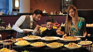 Un bufé con diversos platos y un hombre sirviendo comida a un niño.