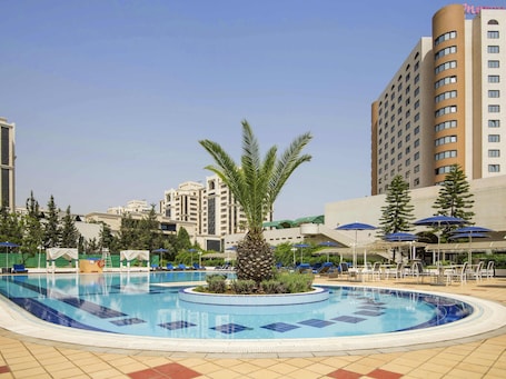 Una piscina al aire libre, sombrillas, sillones reclinables de piscina