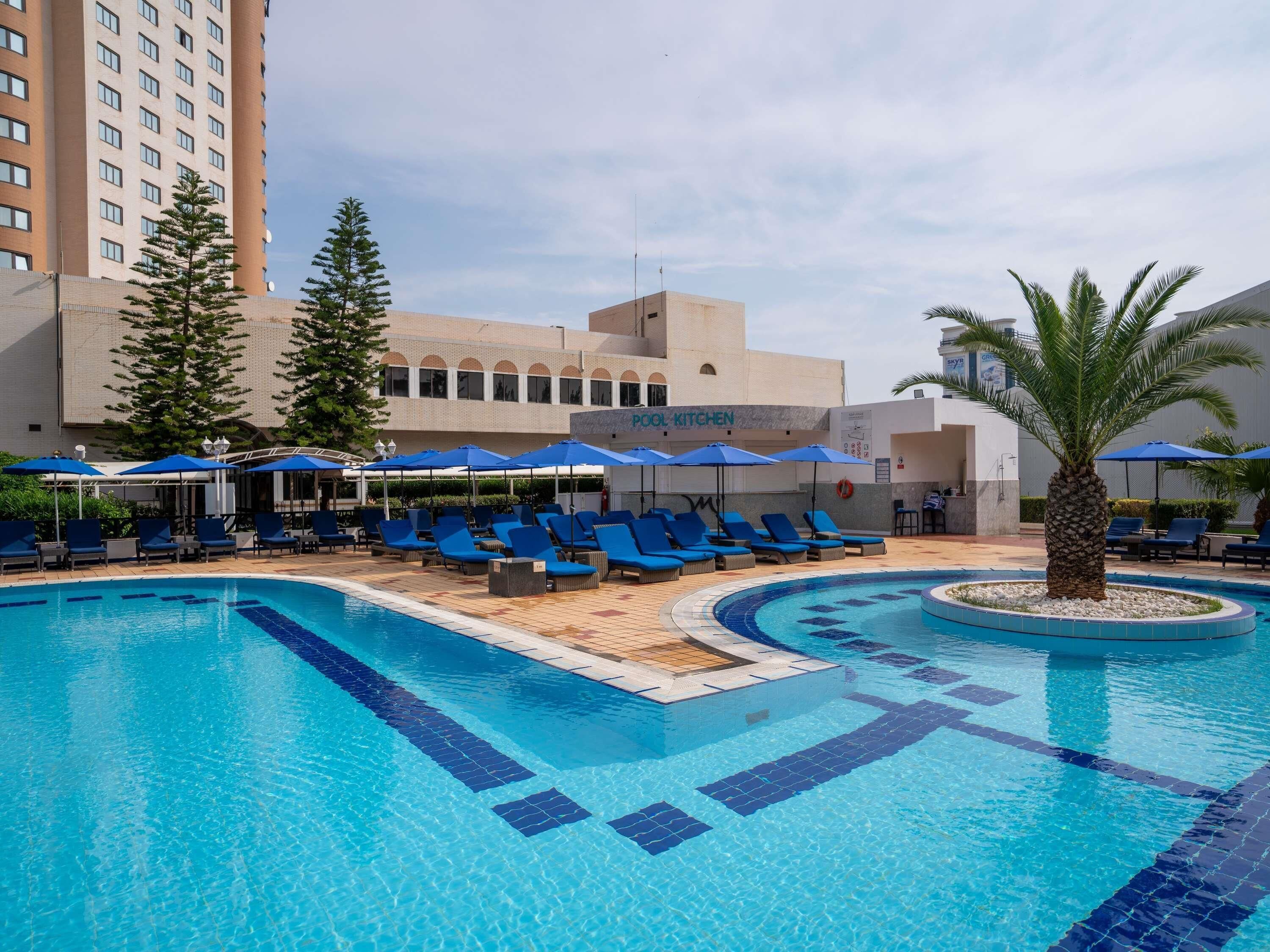 Una piscina al aire libre, sombrillas, tumbonas