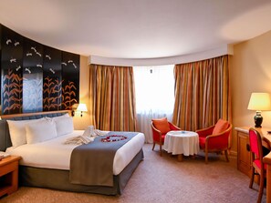 A hotel room with a bed, two chairs, a table, a lamp, and a wall with a leaf pattern. - Mercure Alger Aeroport (Algiers)