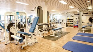 A gym with various exercise equipment, wooden floors, and blue mats. - Mercure Alger Aeroport (Algiers)