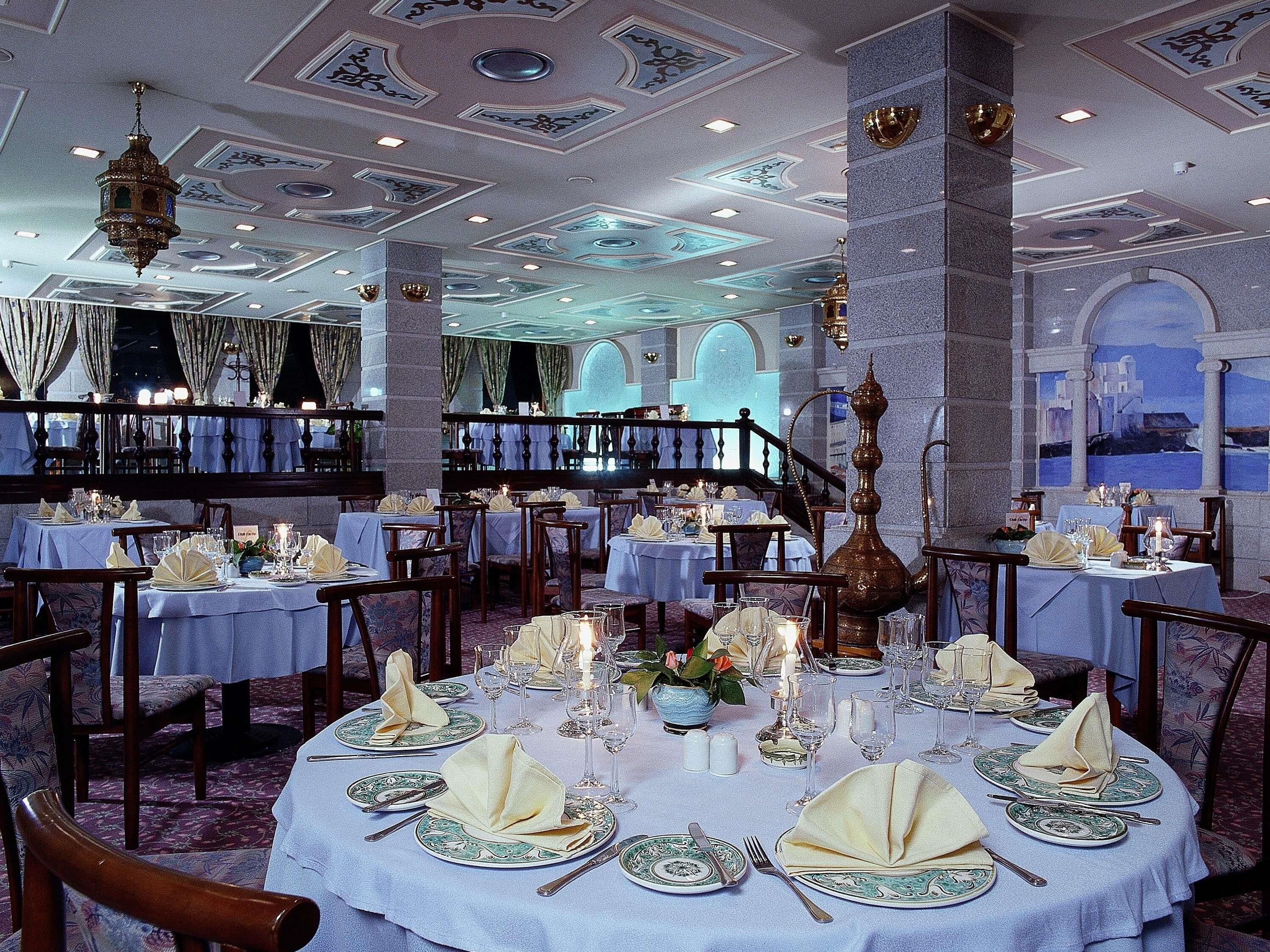 A formal dining room with round tables, elegant table settings, and a chandelier.