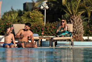 Una piscina al aire libre, sombrillas, sillones reclinables de piscina