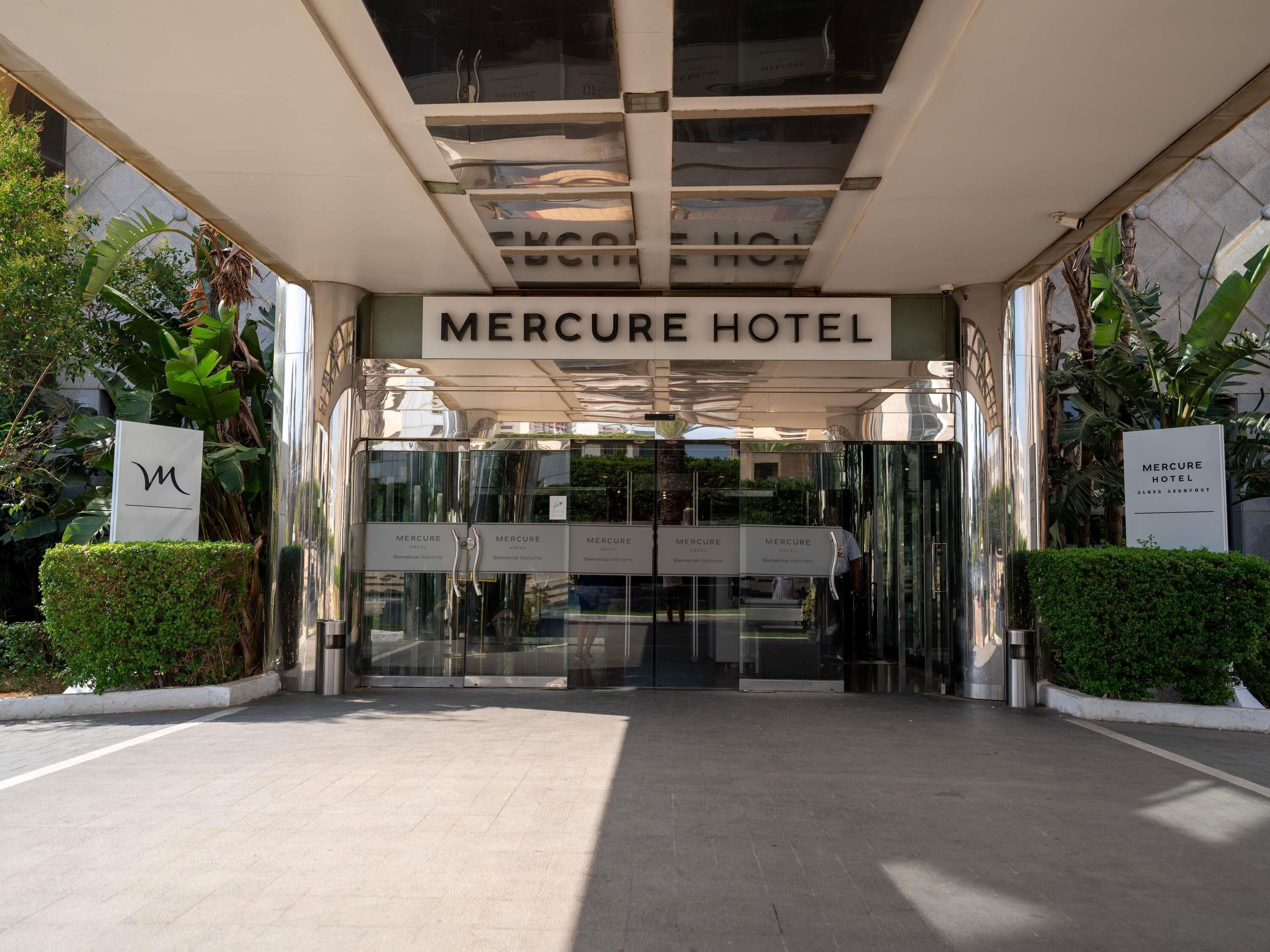The entrance to the Mercure Hotel with a modern design, featuring a glass door entrance and a sign above.