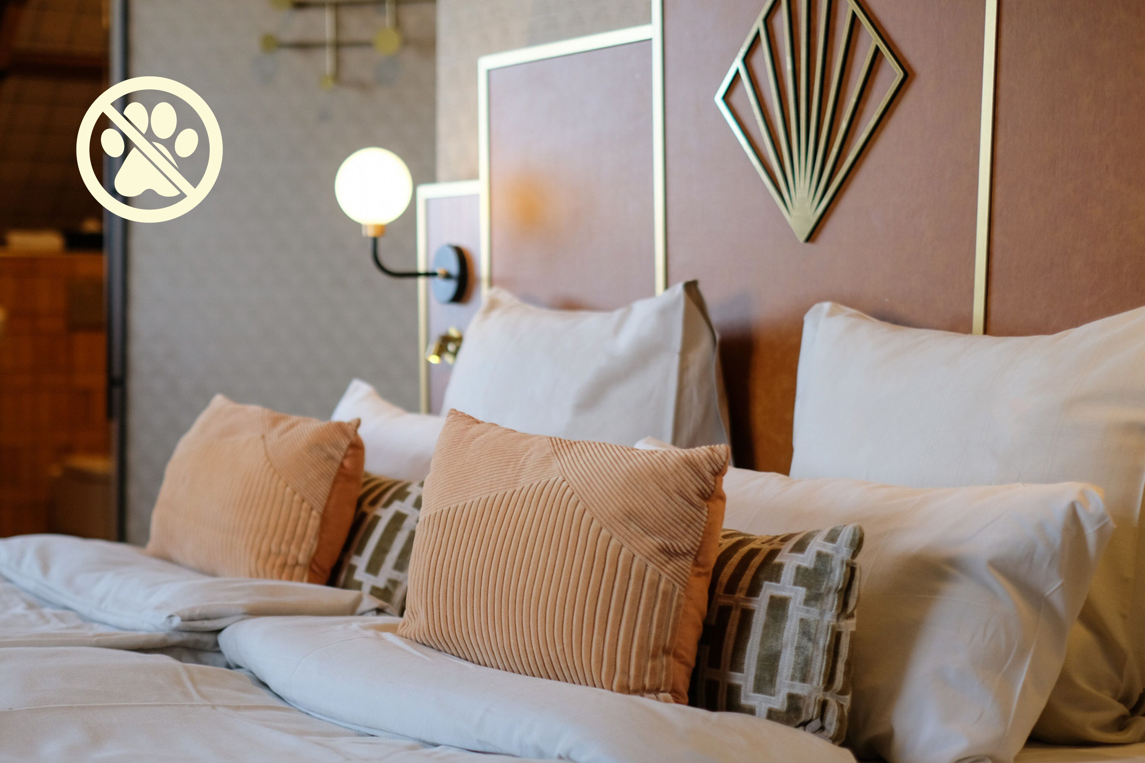 Una cama impecable con muchos almohadones y un cabecero de diseños geométricos.