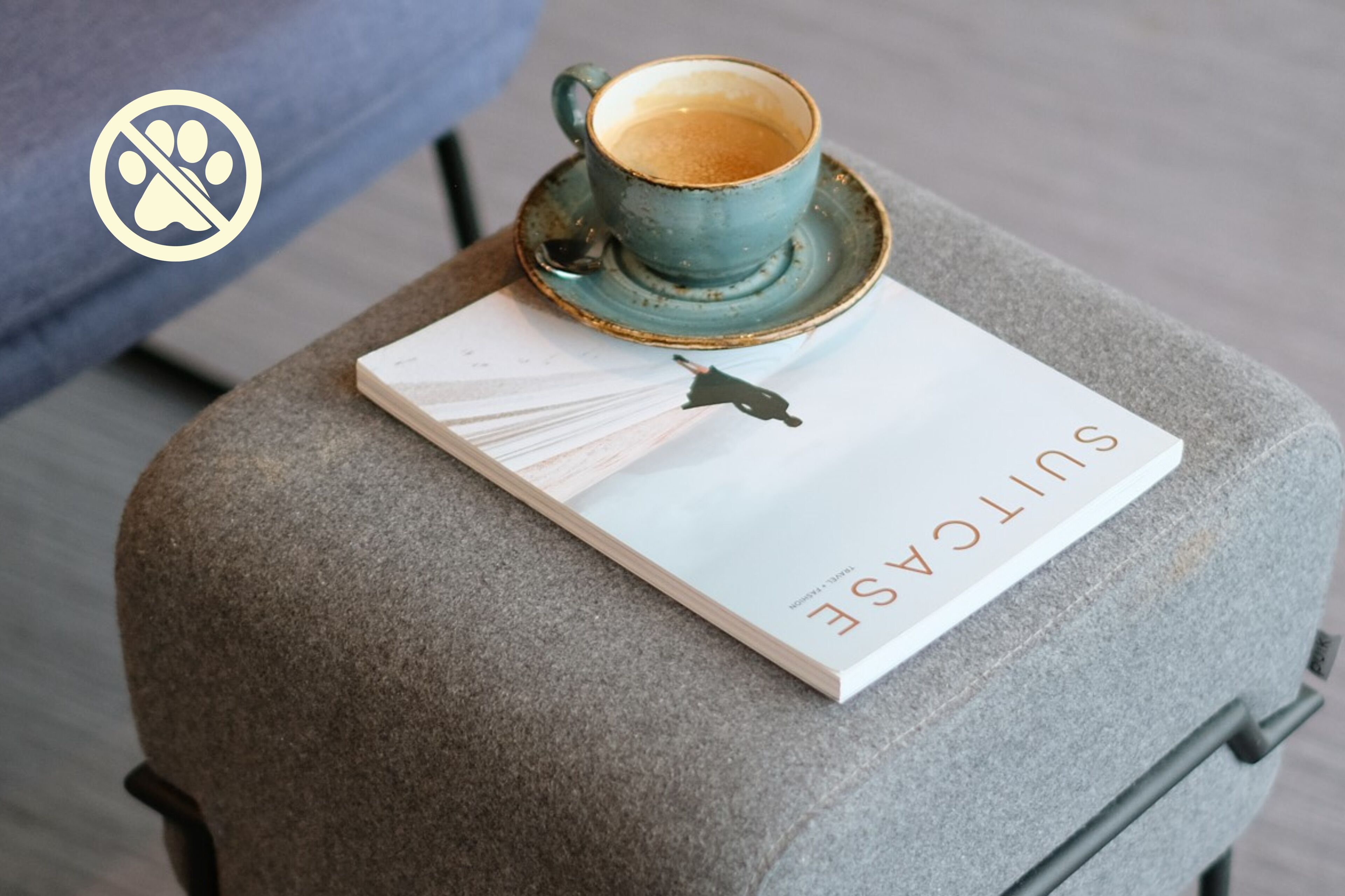A grey suitcase with a book titled "SUTECASE" and a cup of coffee on top.