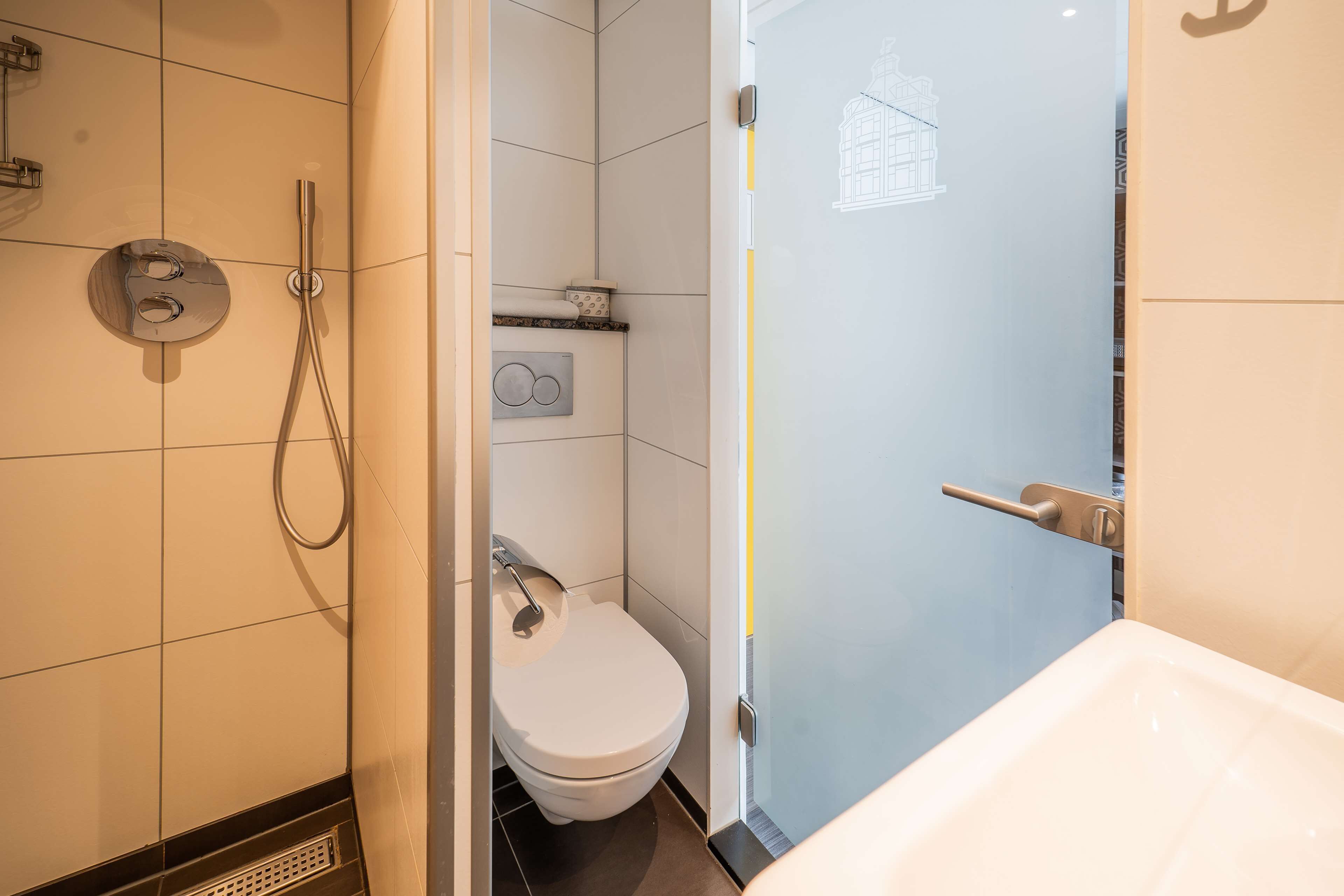 A modern bathroom with a shower, toilet, and sink.
