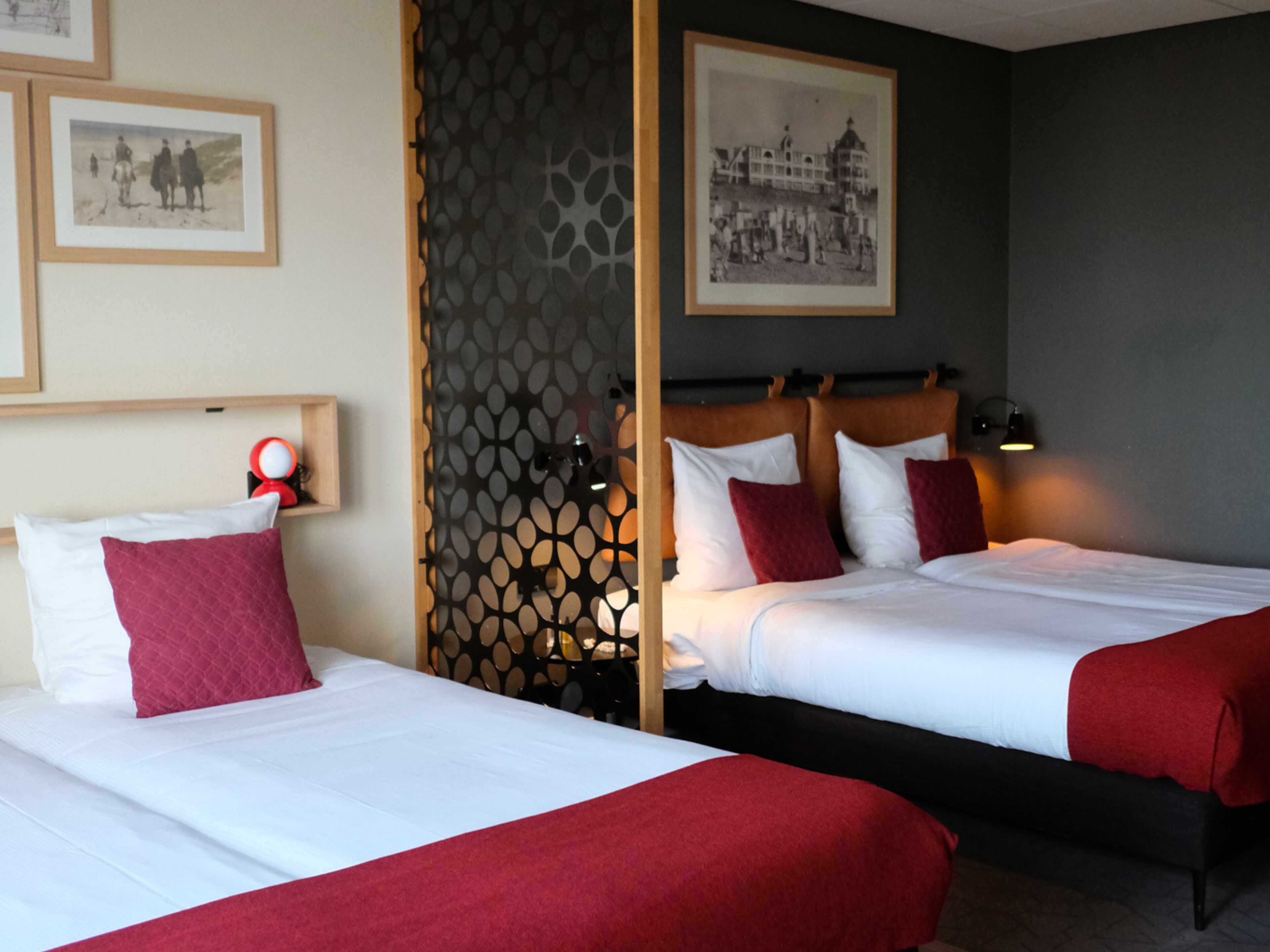 Habitación de hotel con dos camas, un biombo decorativo y cuadros en las paredes.