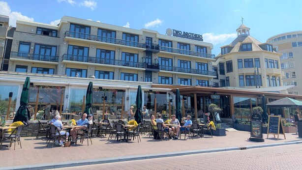 A hotel with outdoor seating, multiple balconies, and a clear sky. - Two Brothers Noordwijk Beach (Noordwijk)