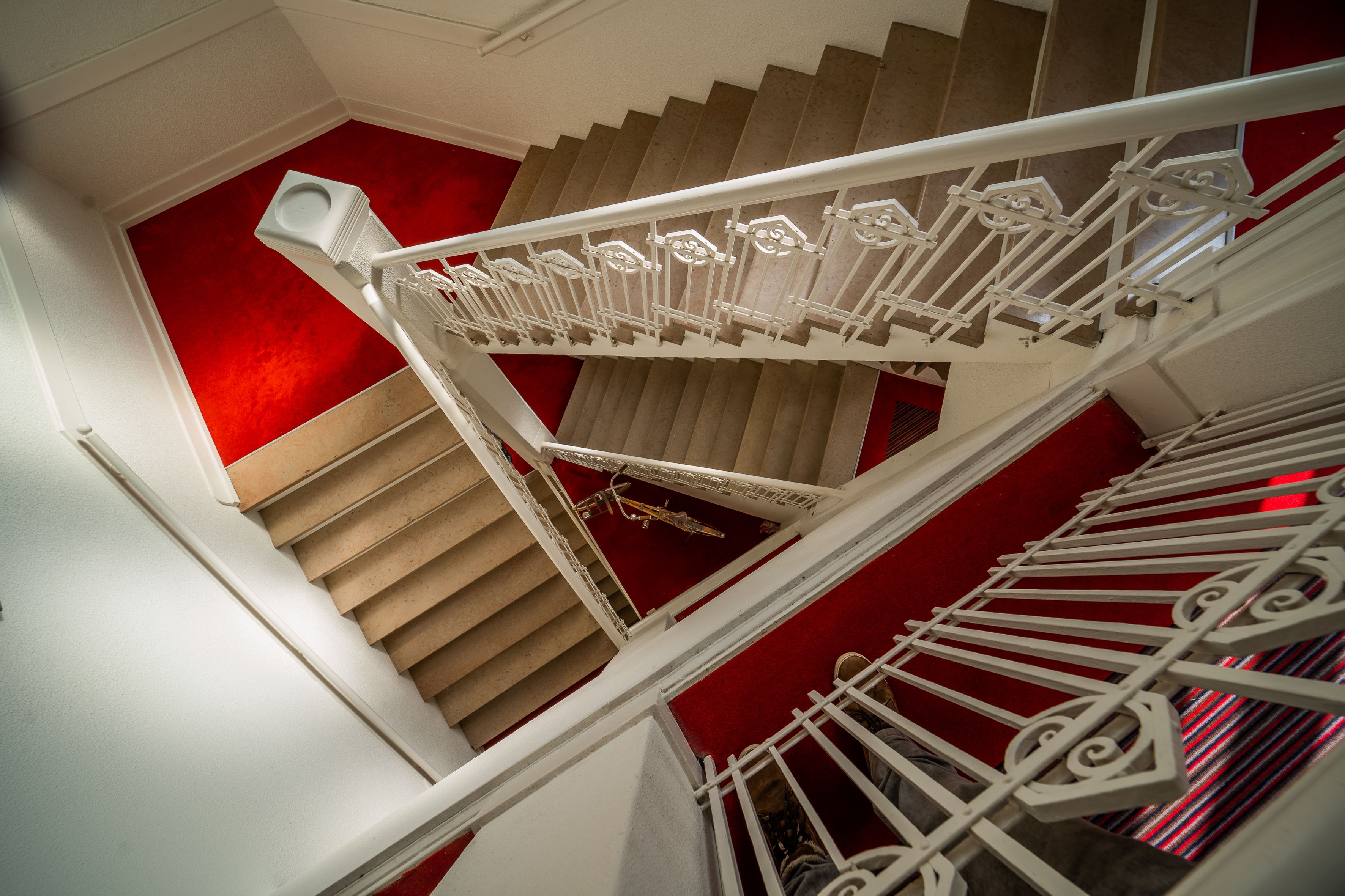 A staircase with white railings and a red wall.