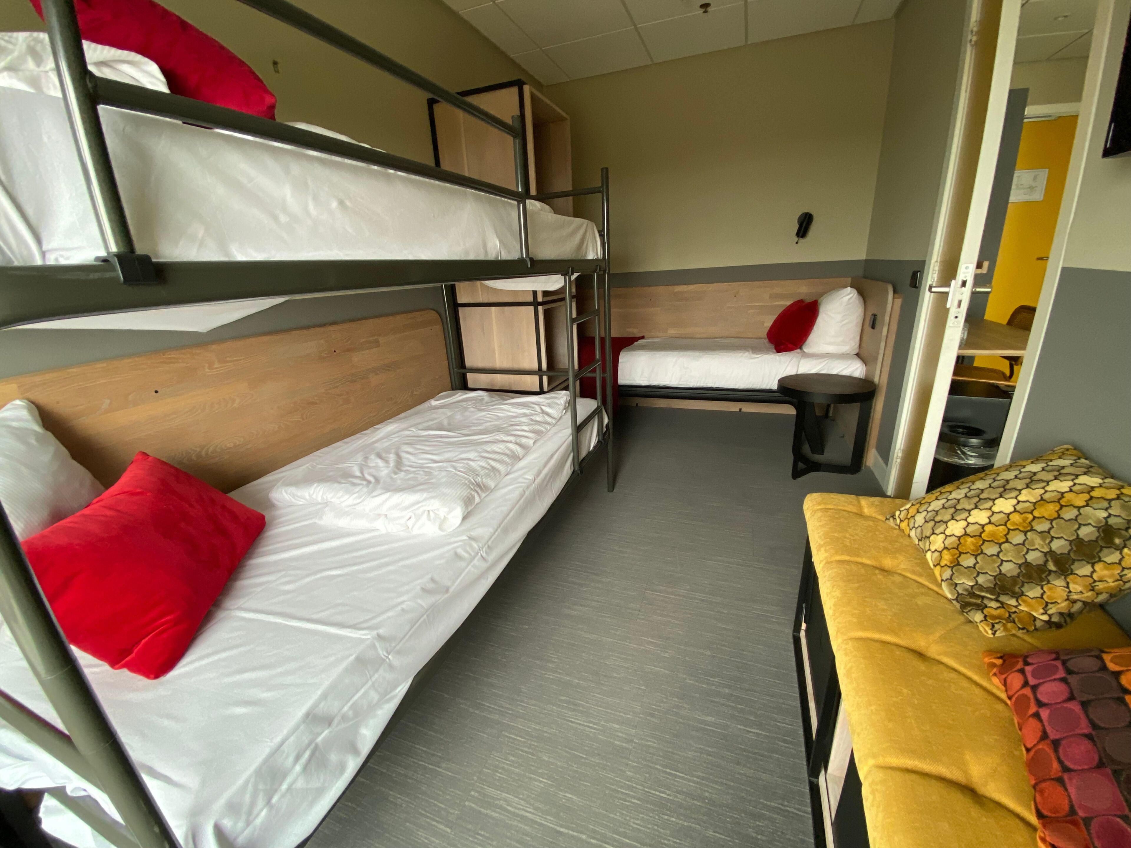 A dormitory room with bunk beds, a single bed, and a small table.