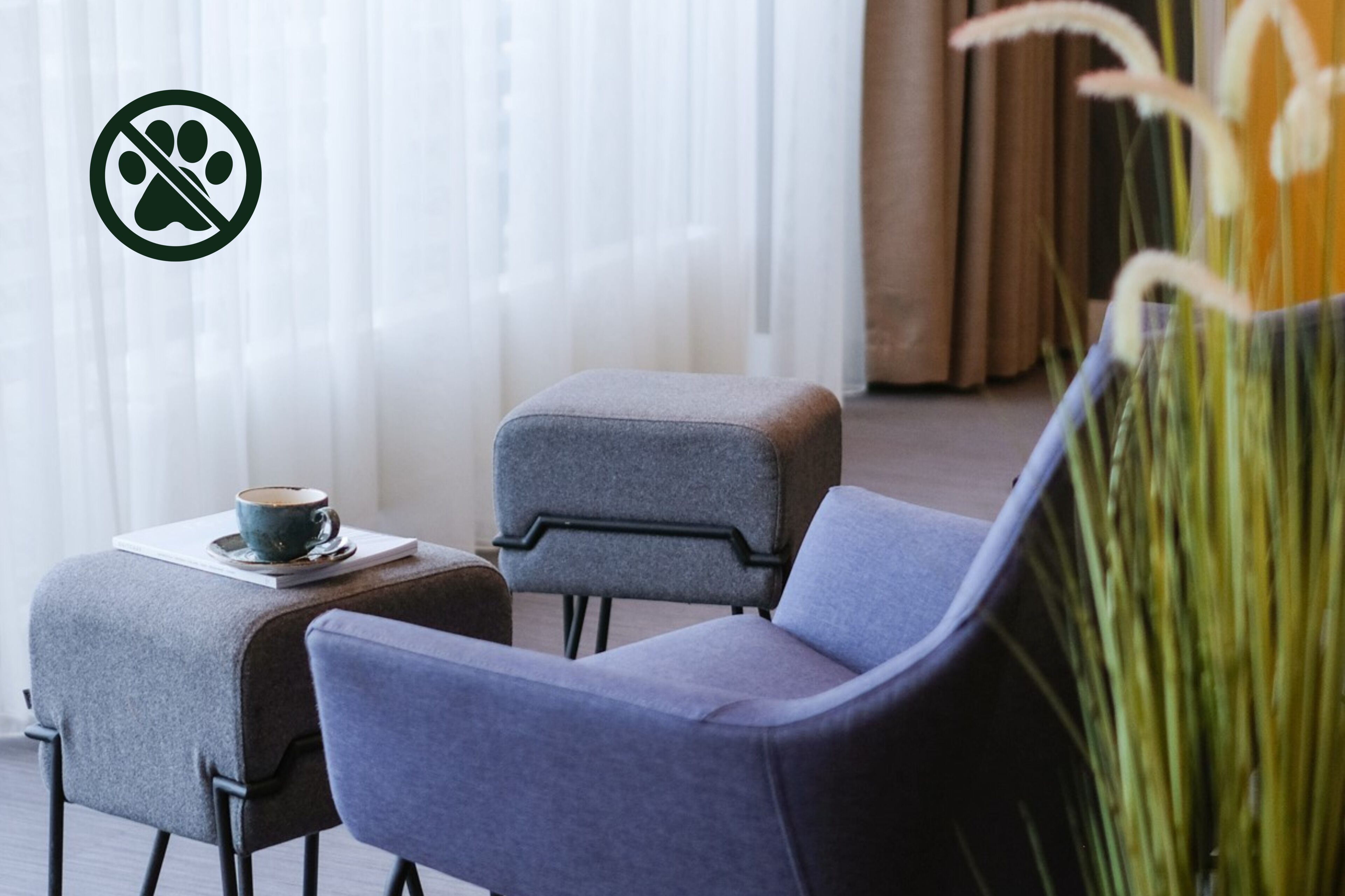A modern room with a grey sofa, a matching ottoman, and a small table with a cup.