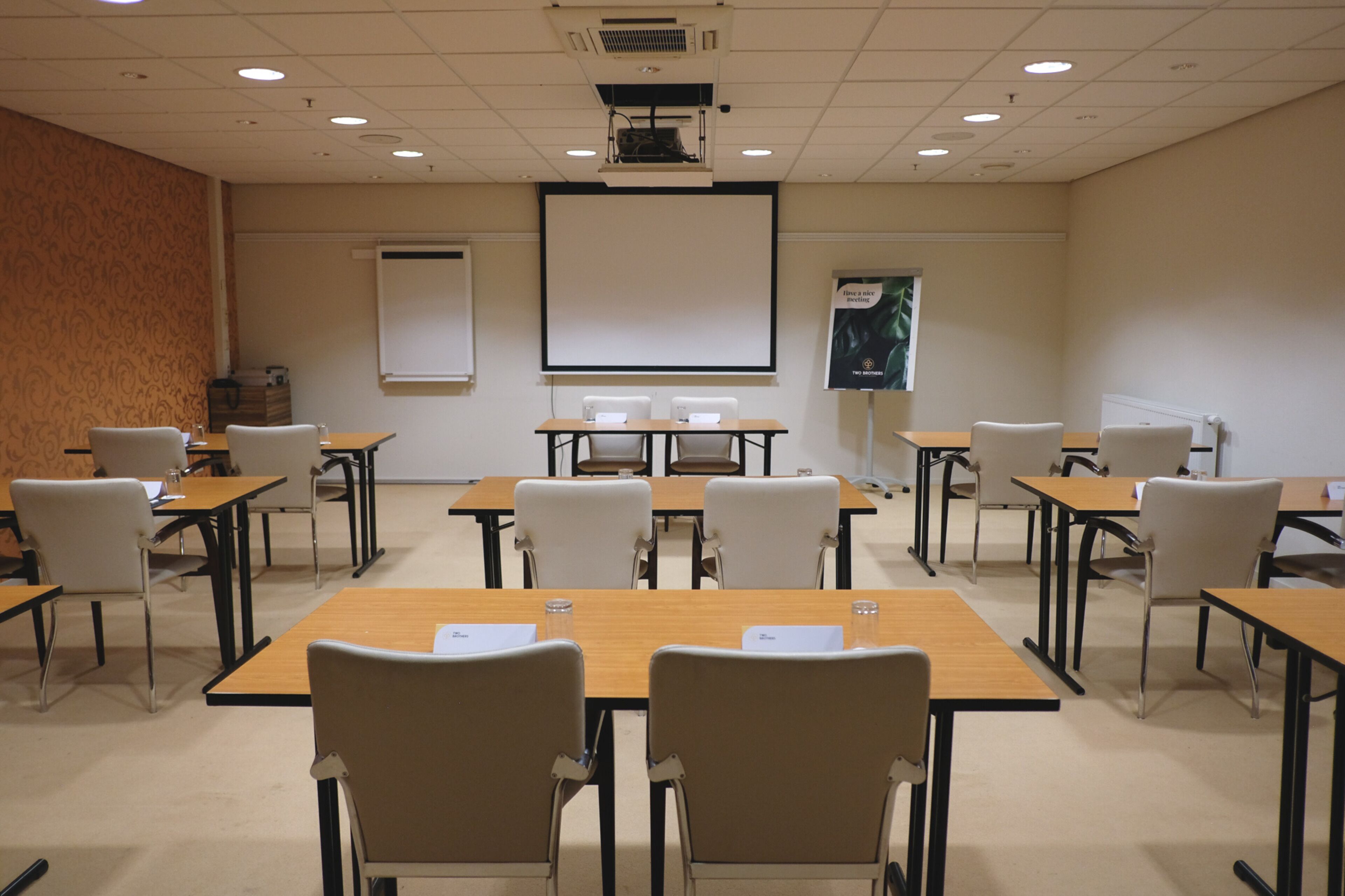 A conference room with multiple tables and chairs, a projector screen, and a presentation screen.