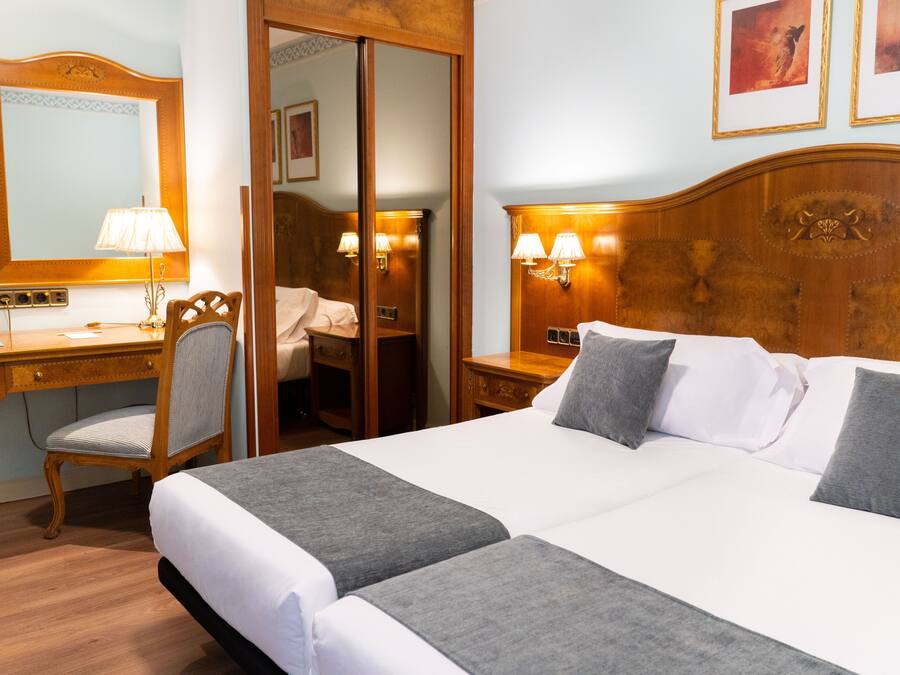 Hotellihuone, jossa on suuri sänky, työpöytä, tuoli ja vaatekaappi.