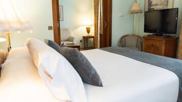 Ein Hotelzimmer mit Bett, Fernseher, Sessel, Lampe und Tür.