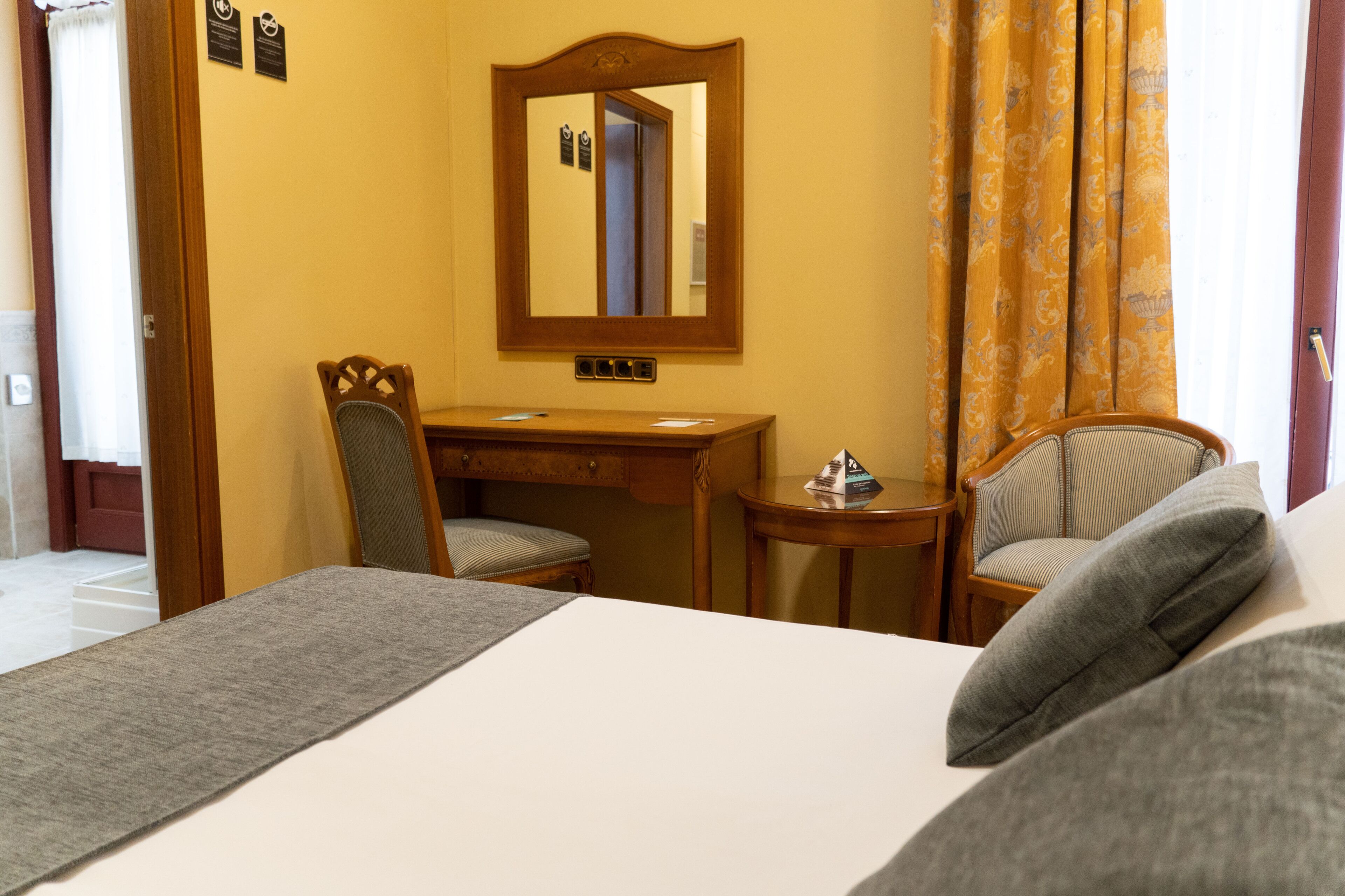 Una habitación de hotel con una cama, un escritorio, una silla y una mesita.