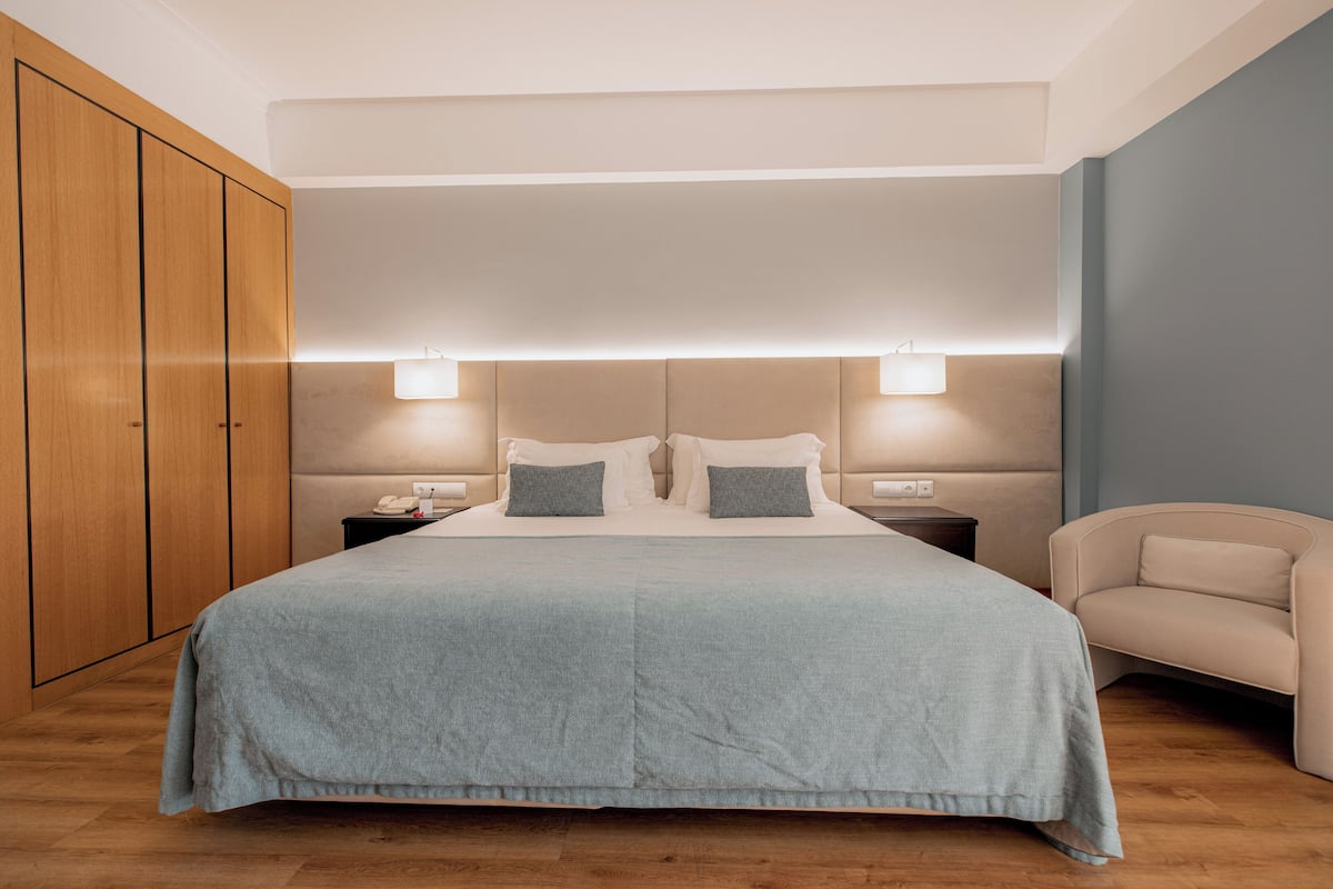 Un dormitorio ordenado con una cama grande, mesitas de noche y un armario.