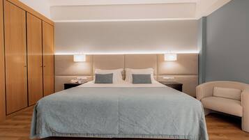 A neatly arranged bedroom with a large bed, bedside tables, and a wardrobe.
