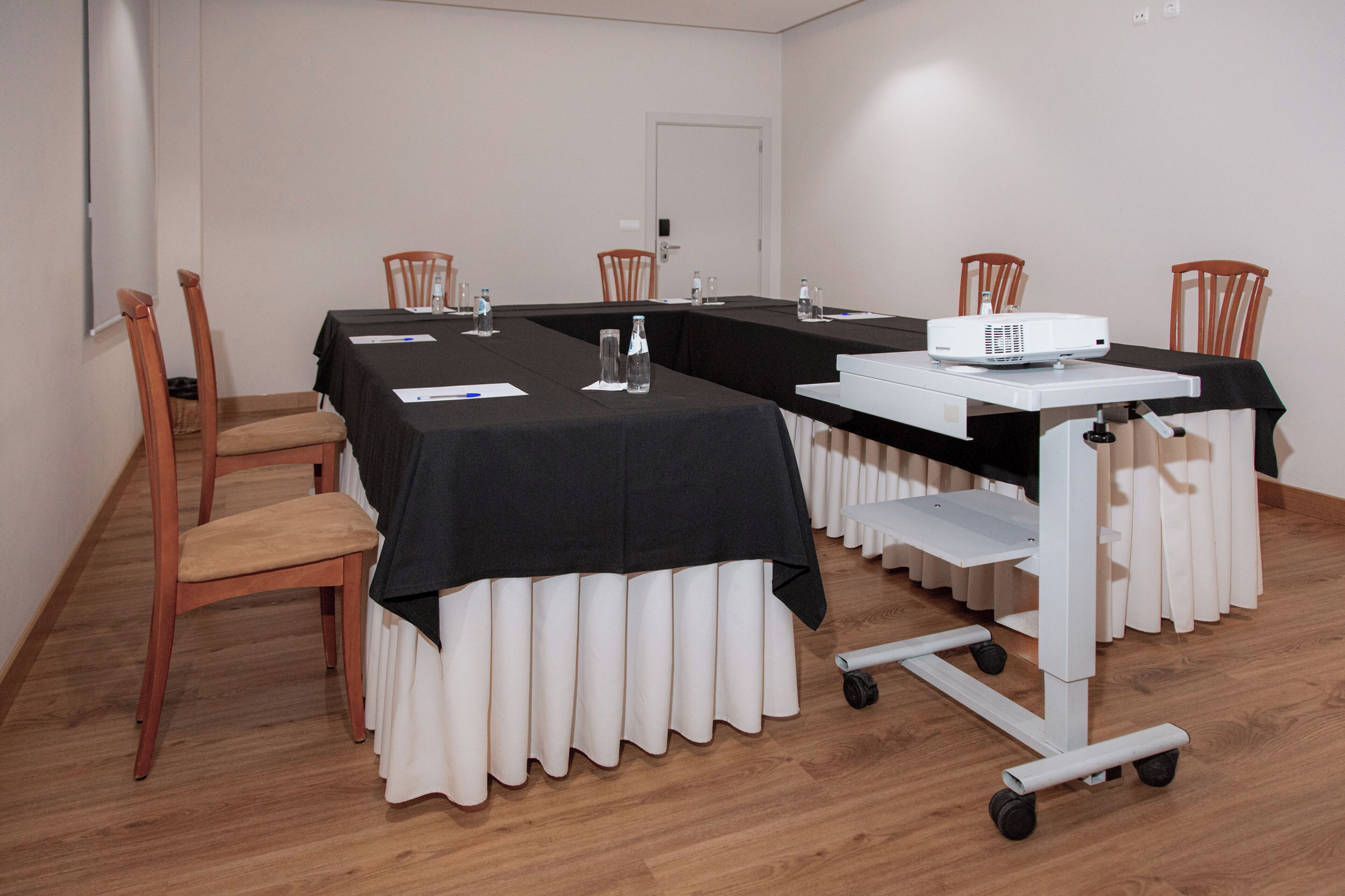A conference room with a long table, chairs, a projector, and a whiteboard.