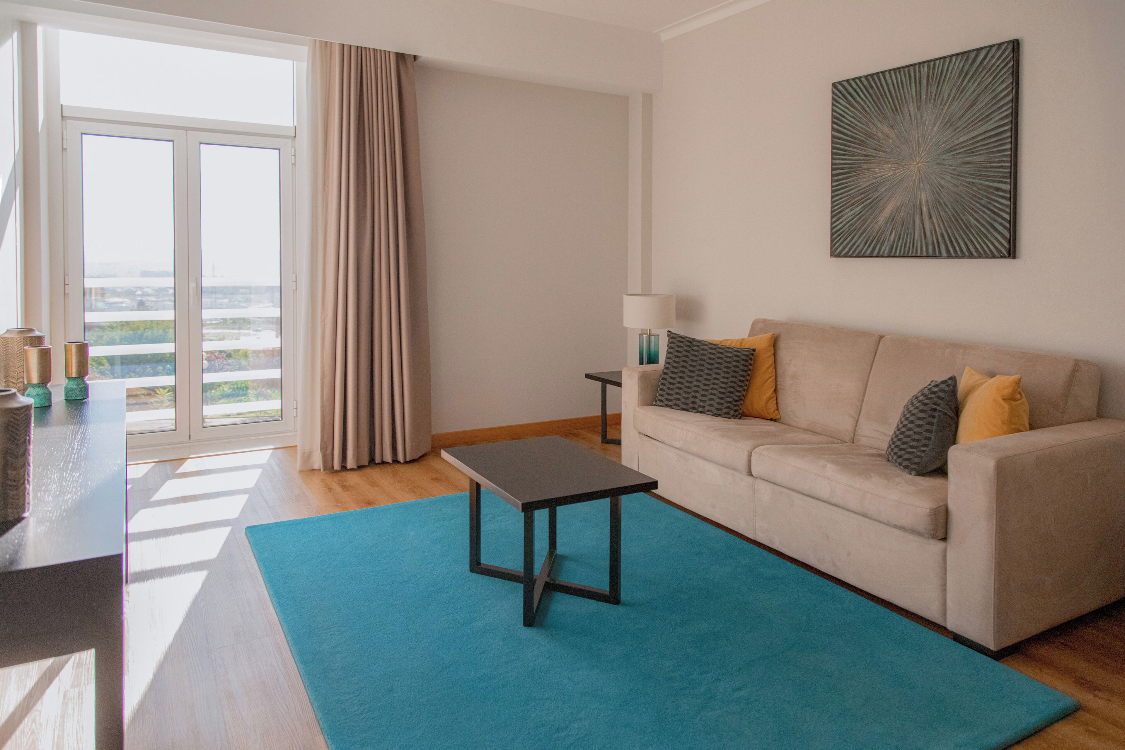A living room with a sofa, a coffee table, a lamp, and a view through a window.