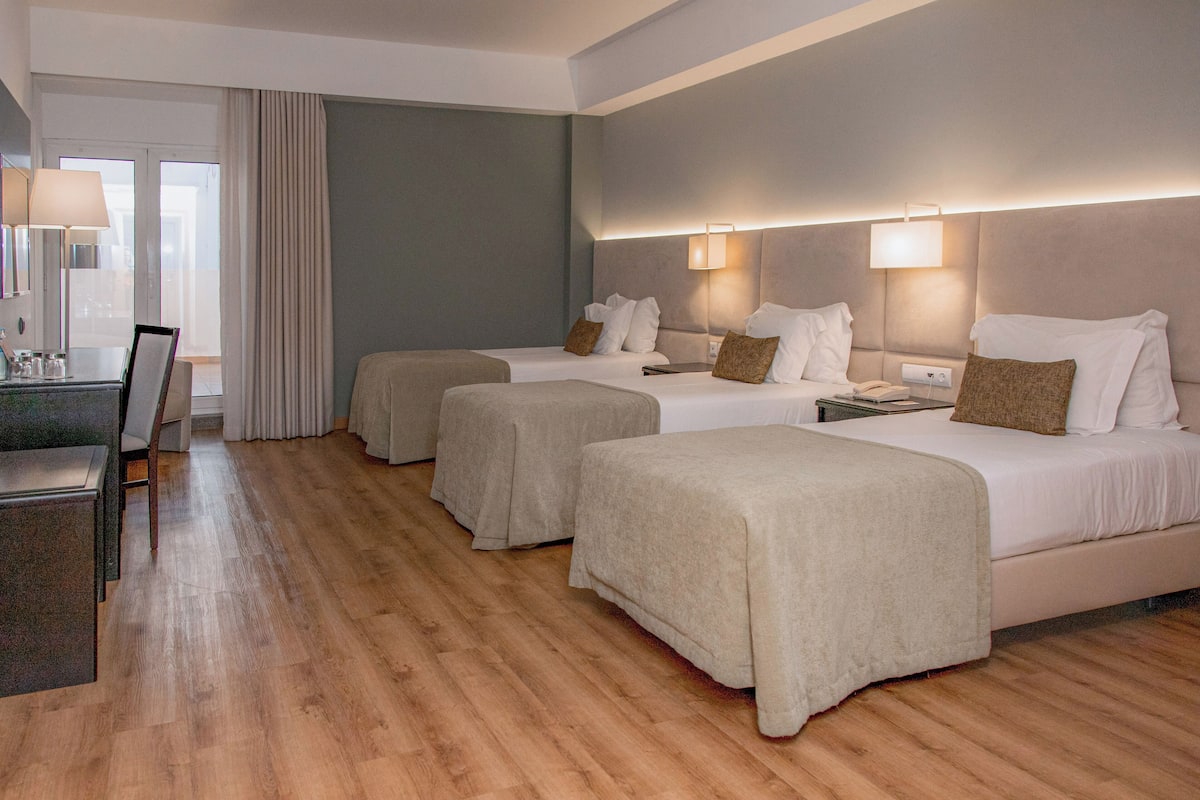 Habitación de hotel con dos camas, un escritorio y una silla.