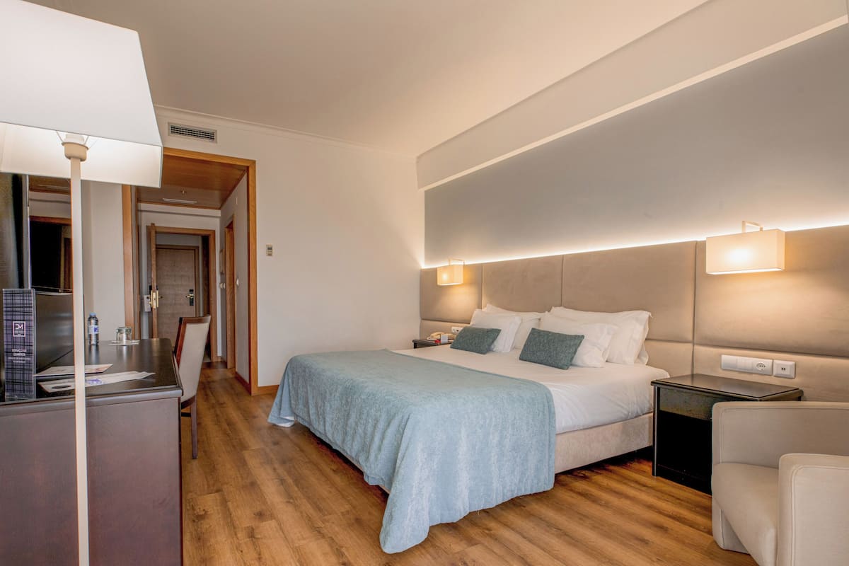 Una habitación de hotel con cama, mesitas de noche, escritorio y silla.