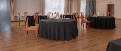 Un salón de conferencias con mesas redondas, sillas y un diseño de interiores moderno.