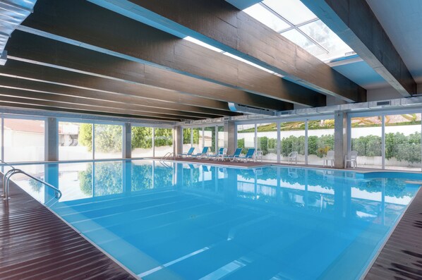 Una piscina techada, sillones reclinables de piscina