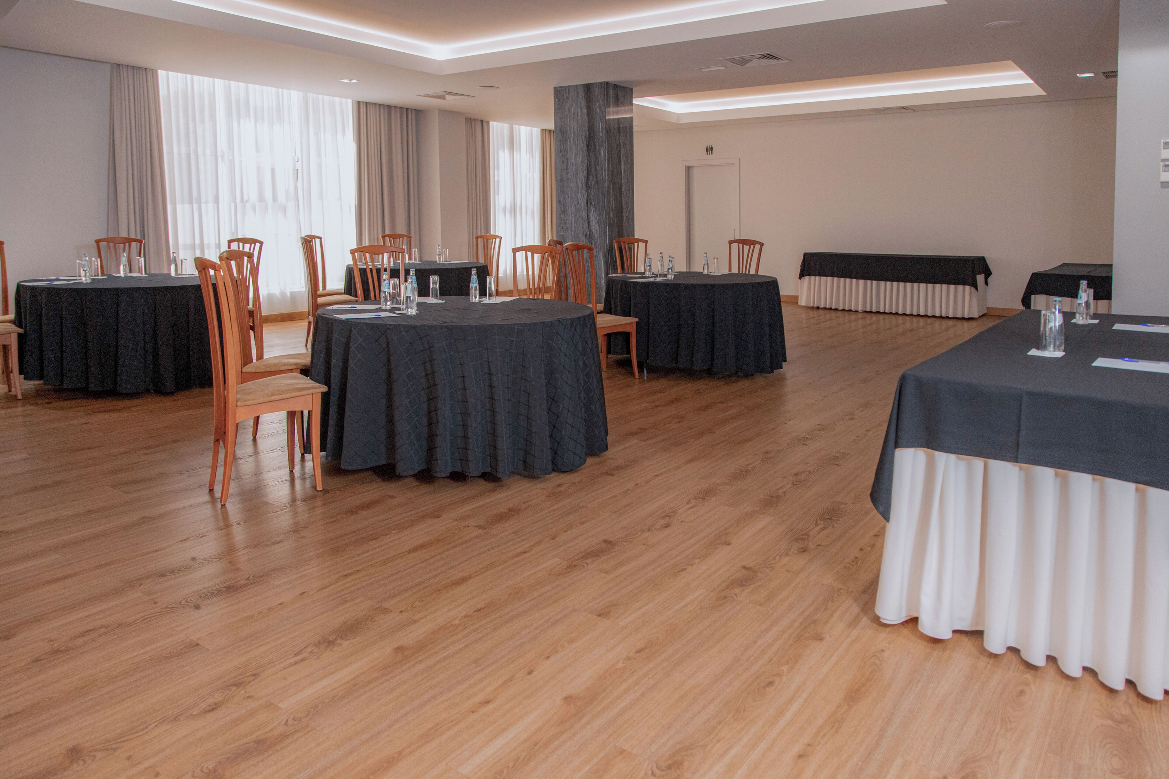 A conference room with round tables, chairs, and a black tablecloth.