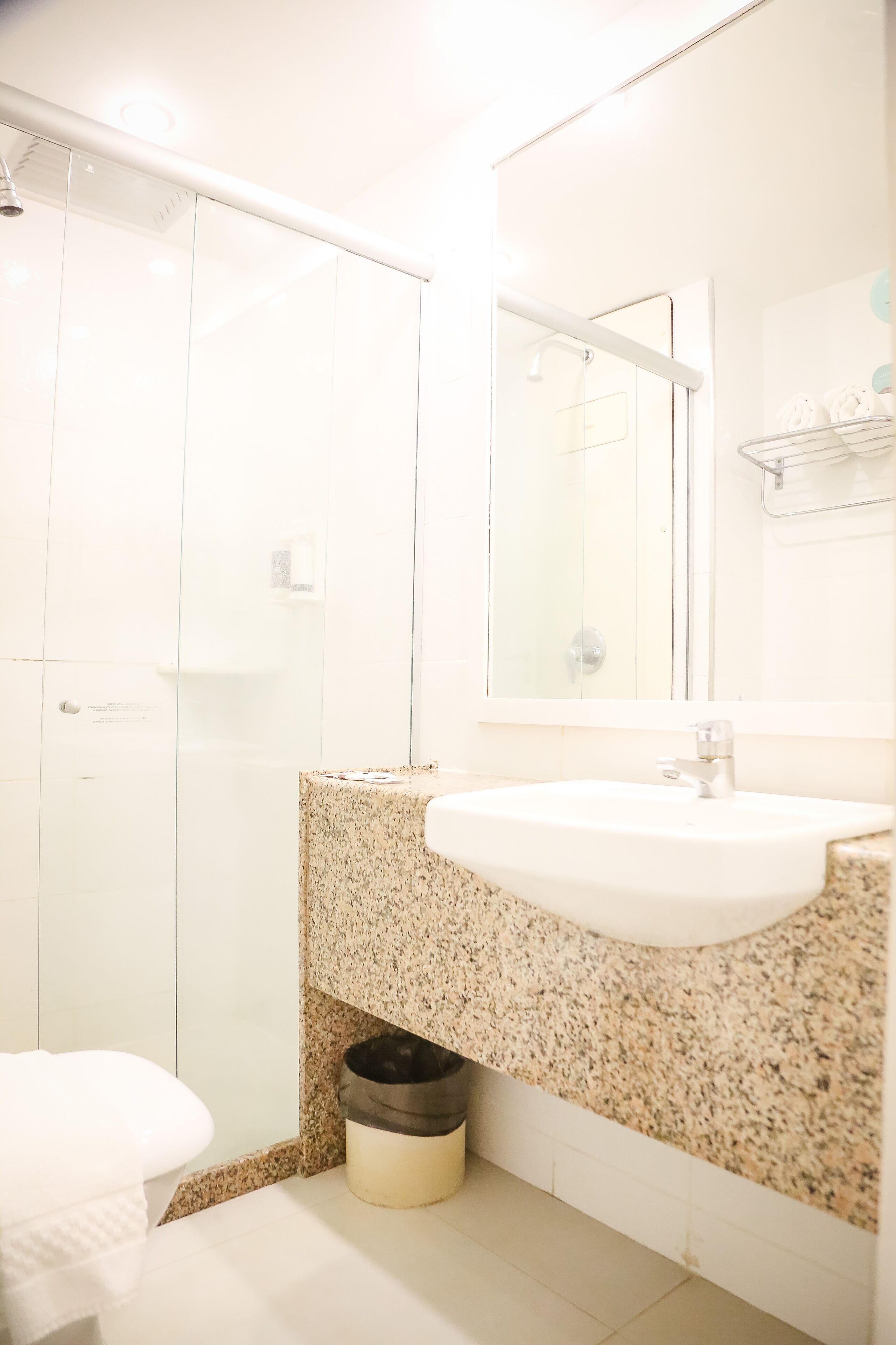 A bathroom with a white sink, granite countertop, and a glass shower enclosure.