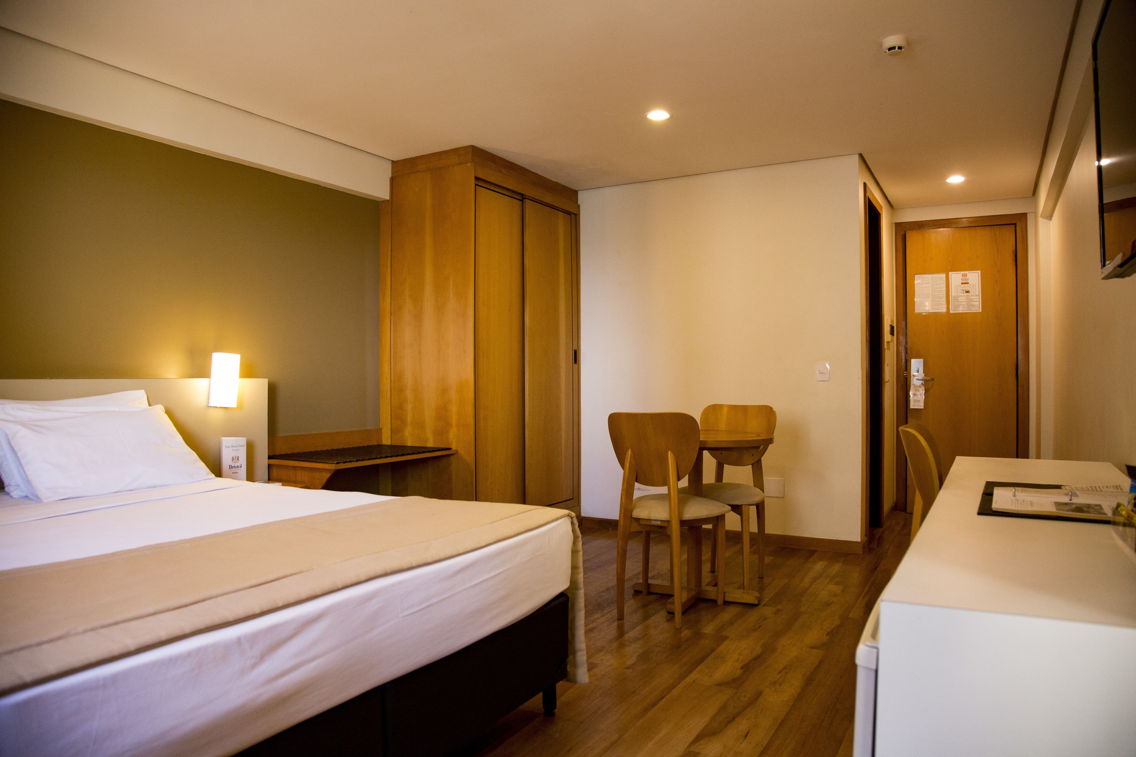 Habitación de hotel con cama, escritorio, dos sillas y una mesita.
